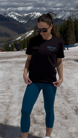 Person standing on a snowy road with mountains in the background