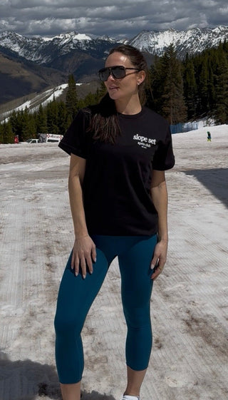 Person standing in a snowy landscape with mountains and clouds in the background