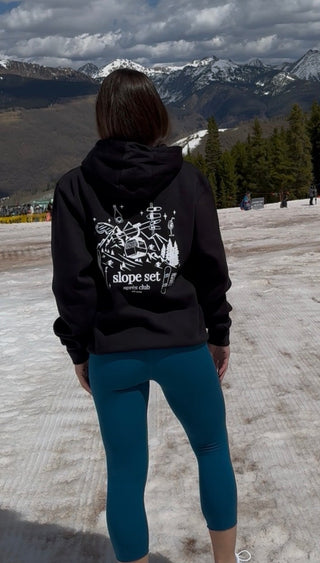 Person wearing a black hoodie with a mountain view in the background